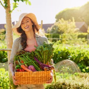 Young woman carrying a basket of freshly picked produce in a garden